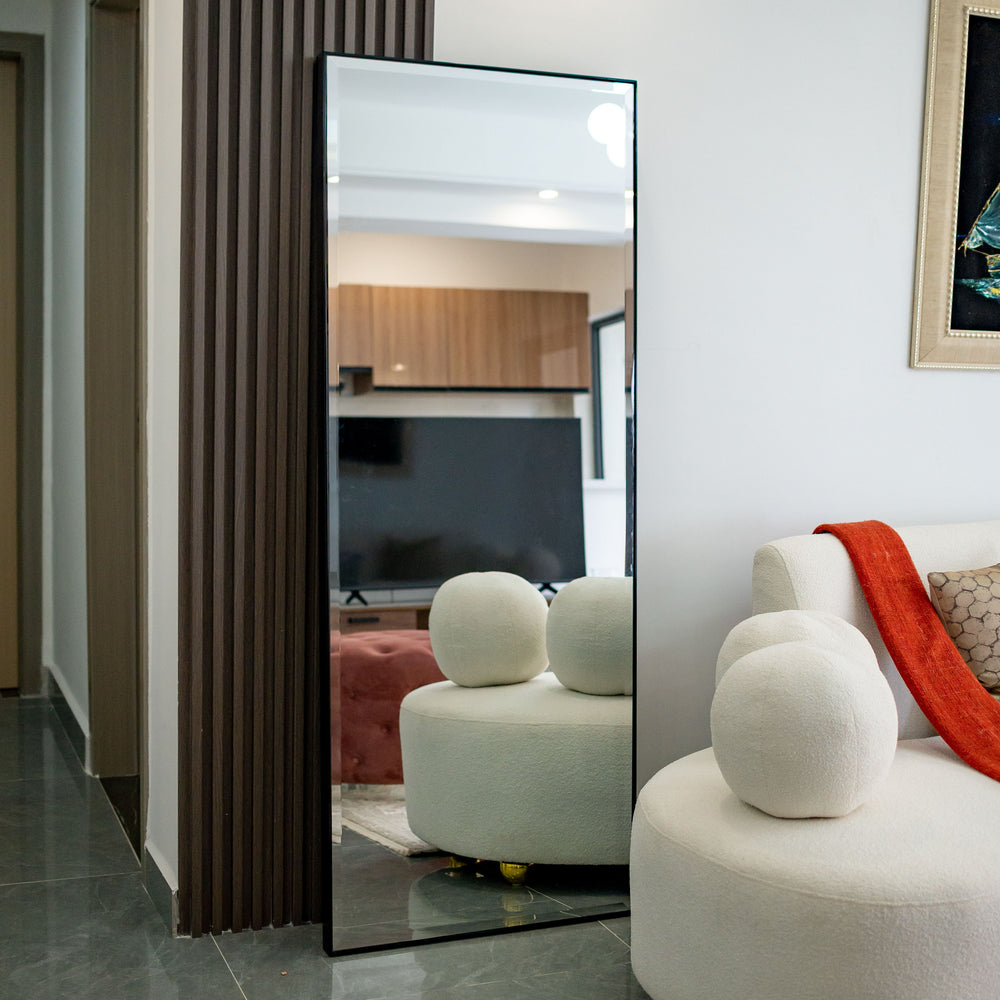 Modern living room with a large mirror reflecting a television and another room.