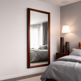 Large floor mirror with wooden frame in a bedroom setting