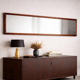 Long wooden mirror above a dark wooden console table with decorative items.