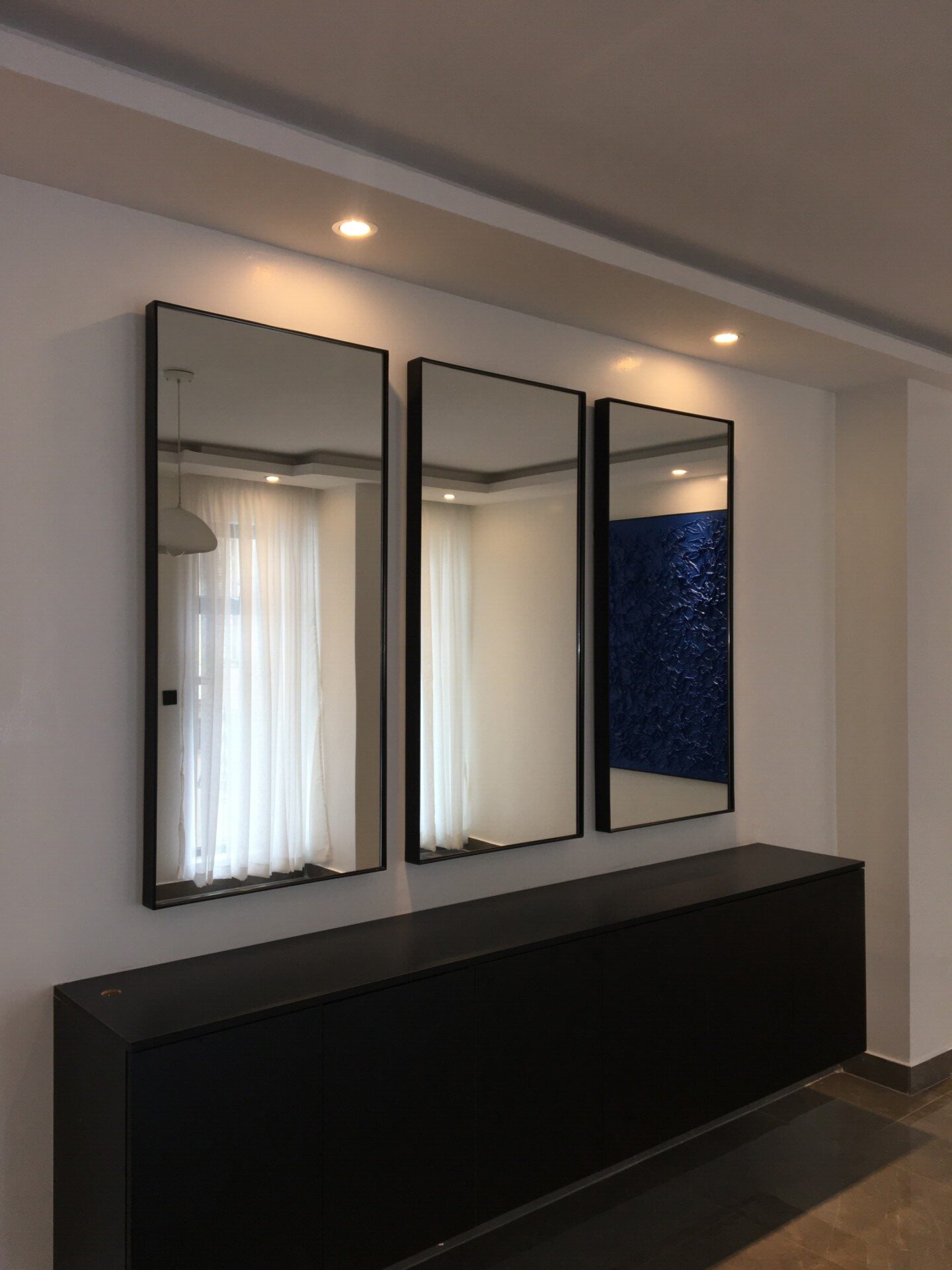 Modern, sleek mirror with a minimalist frame, reflecting a softly lit room, emphasizing contemporary interior design